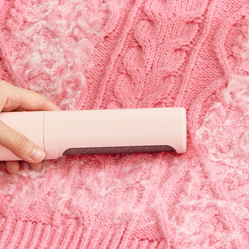 Pink reusable pet-hair remover cleaning lint from a knitted blanket